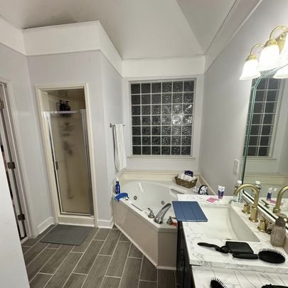 A cozy bathroom view with a glass shower, a large soaking tub, and ample natural light from a window.